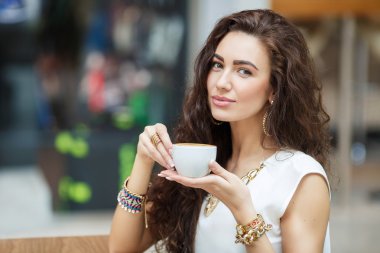 Woman drinking coffee in a cafe supermarket. clipart