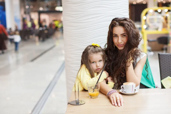 Mamá y su hija beben café y jugo en un supermercado de café . — Foto de Stock