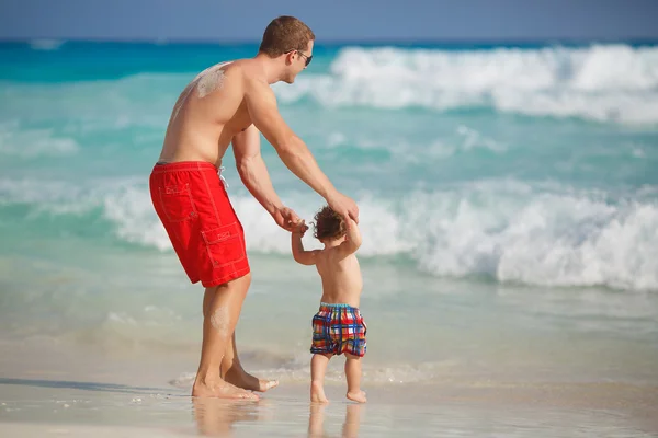 年轻的父亲，靠近海洋的年幼的儿子玩. — 图库照片