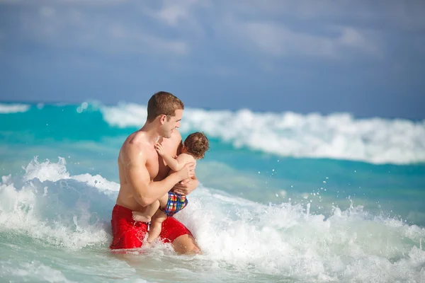 Jovem pai com um jovem filho brincar perto do oceano . — Fotografia de Stock