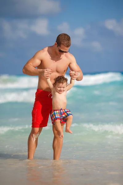 Jonge vader met een jonge zoon spelen in de buurt van de Oceaan. — Stockfoto