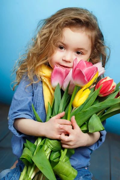 Beautiful little girl with a big bouquet of tulips. — Stock Photo, Image