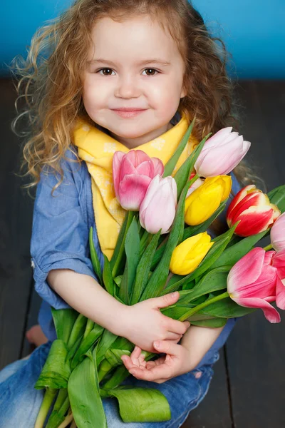 Beautiful little girl with a big bouquet of tulips. — Stock Photo, Image