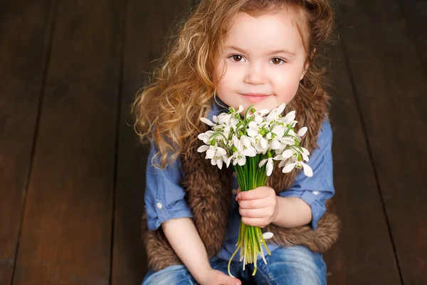 Belle petite fille avec un gros bouquet de gouttes de neige . — Photo