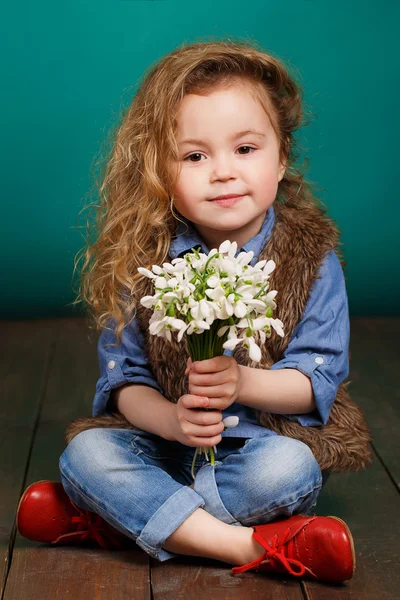 Beautiful little girl with a big bouquet of snowdrops. — Stock Photo, Image