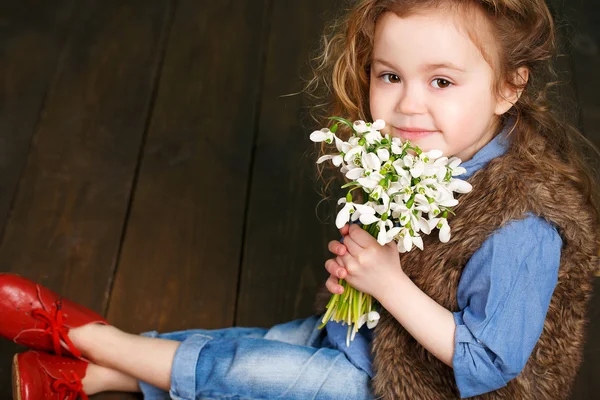 Krásná holčička s velkou kyticí sněženky. — Stock fotografie