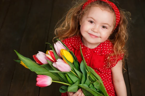 Krásná holčička s velkou kyticí tulipánů. — Stock fotografie