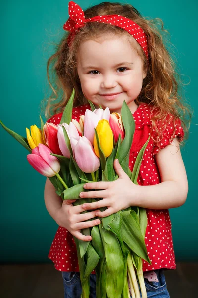 Schönes kleines Mädchen mit einem großen Strauß Tulpen. — Stockfoto