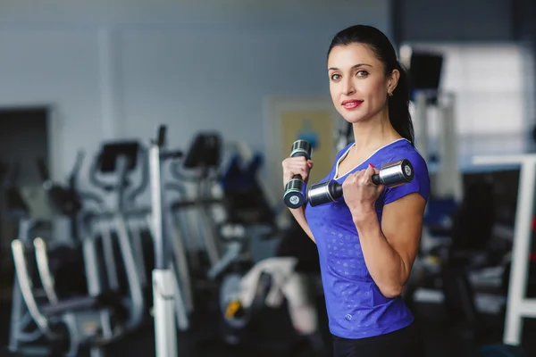 Portret van een mooie jonge sportieve vrouw met halters in haar handen. — Stockfoto