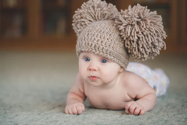 見上げて、床に横たわって、帽子の新生の女の子. — ストック写真