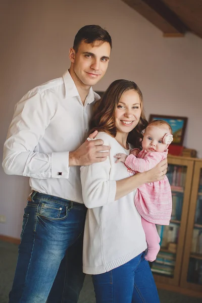 Happy young family with a small child in her arms. — Stock Photo, Image