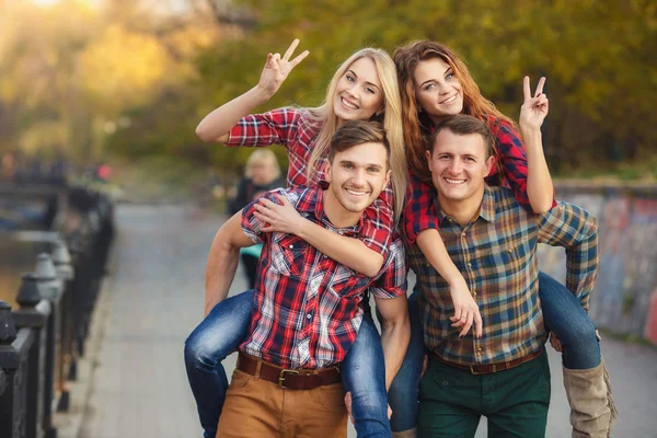 Vier gute Freunde entspannen und haben Spaß im Herbstpark. — Stockfoto