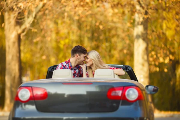 Casal amoroso em um conversível preto no parque de outono . — Fotografia de Stock