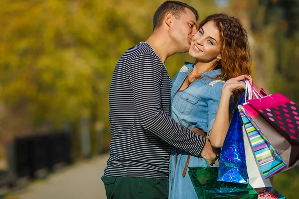 Jovem casal feliz com um saco de papel em um parque no outono . — Fotografia de Stock