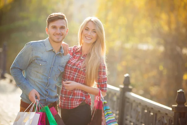 Jovem casal feliz com um saco de papel em um parque no outono . — Fotografia de Stock