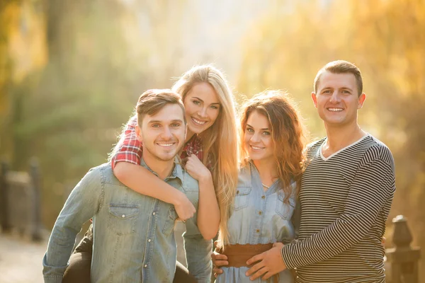 Vier gute Freunde entspannen und haben Spaß im Herbstpark. — Stockfoto