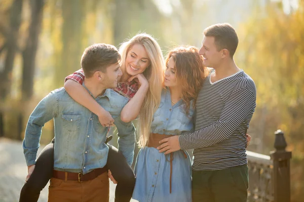 Quattro buoni amici rilassarsi e divertirsi nel parco autunnale . — Foto Stock