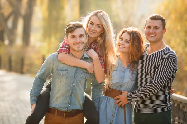 Vier gute Freunde entspannen und haben Spaß im Herbstpark. — Stockfoto