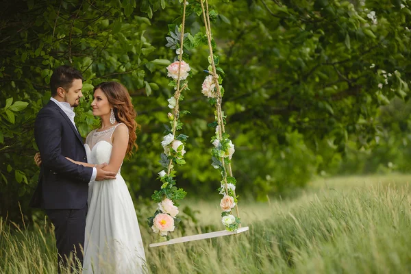 Groom swings the bride on a swing in outdoor park — Stock Photo, Image