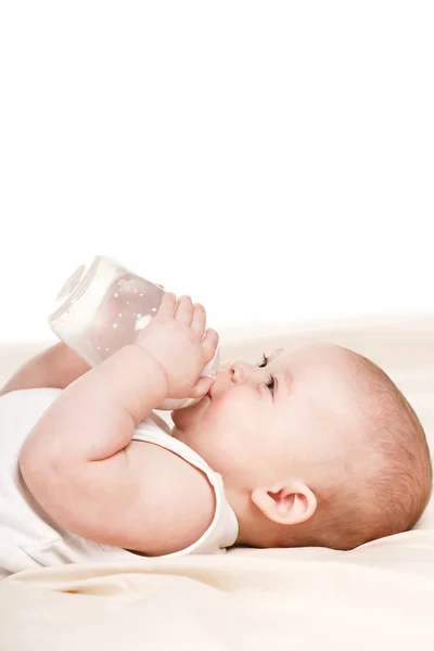 Lindo bebé con un biberón de leche en una manta beige — Foto de Stock