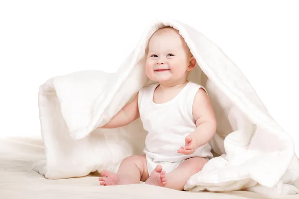 Bebê bonito espreitando debaixo do cobertor, brincando na cama . — Fotografia de Stock