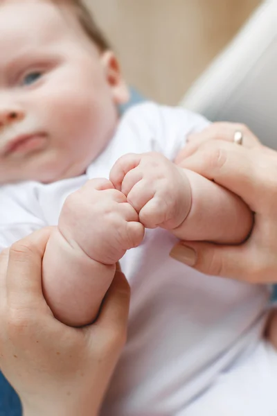 Una madre sostiene tiernamente la mano de un bebé recién nacido . —  Fotos de Stock