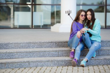 İki genç çekici kadın sokaklardaki bir smartphone ile fotoğraflandı.