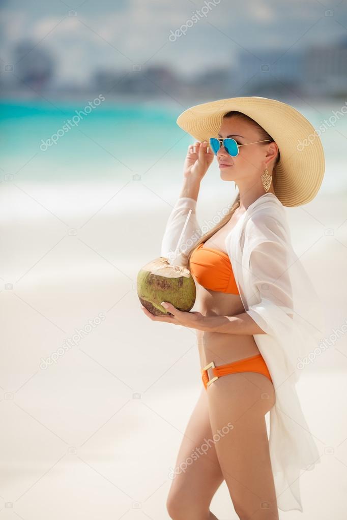 Beautiful lady in a bikini, removes thirst with coconut milk