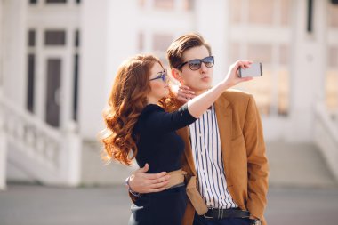 The couple is photographed with smartphone in the city clipart