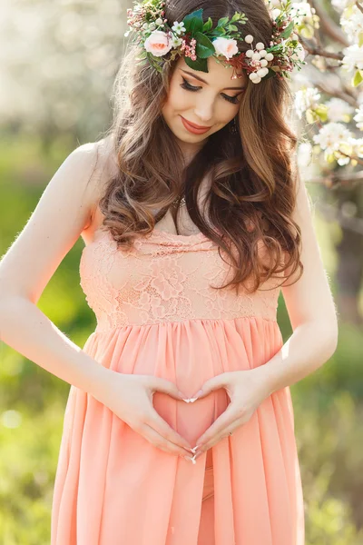 Heart shaped hands of pregnant woman on her belly — Stock Photo, Image