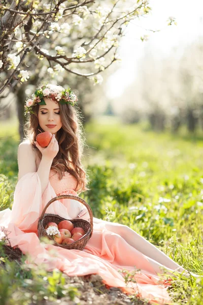 Mulher grávida no jardim da primavera com uma cesta de maçãs maduras . — Fotografia de Stock