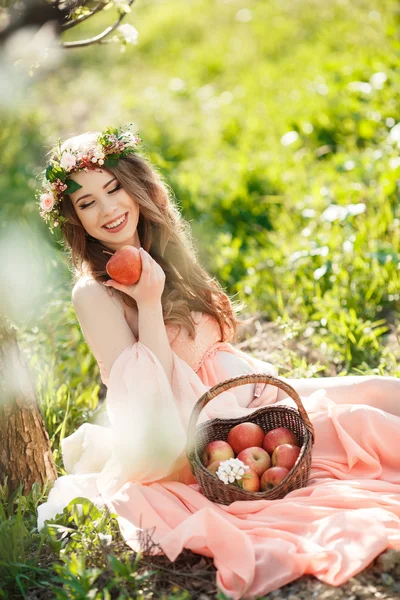 Mujer embarazada en el jardín de primavera con una cesta de manzanas maduras . — Foto de Stock