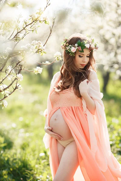 Όμορφη έγκυο γυναίκα σε έναν κήπο λουλουδιασμένη ανοιξιάτικη. — Φωτογραφία Αρχείου