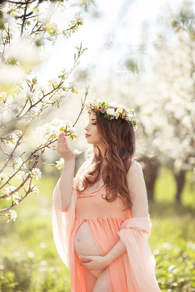 Kaunis raskaana oleva nainen kukkaisessa kevätpuutarhassa . — kuvapankkivalokuva