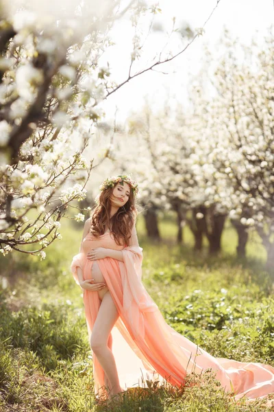 Krásná těhotná žena v jarní květinová zahrada. — Stock fotografie