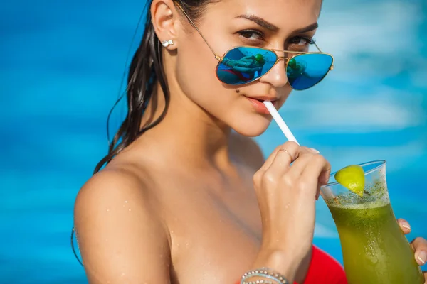 Elegante junge Frau im Pool mit einem Cocktail. — Stockfoto