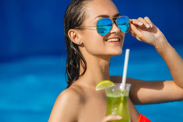 Elegante junge Frau im Pool mit einem Cocktail. — Stockfoto