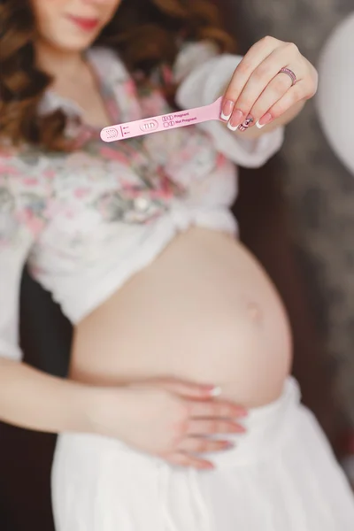 Pregnant woman holding a pregnancy test. Close-up. — Stock Photo, Image