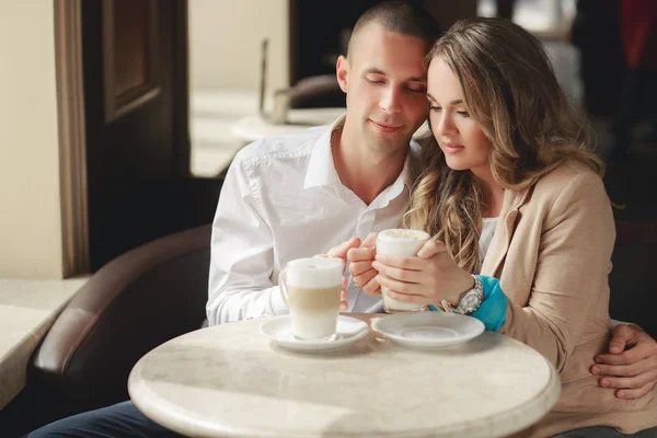 Happy couple drinking coffee in an urban café. — Stockfoto