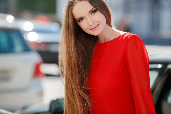 Jovem mulher bonita de pé na rua da cidade com carro novo no fundo — Fotografia de Stock