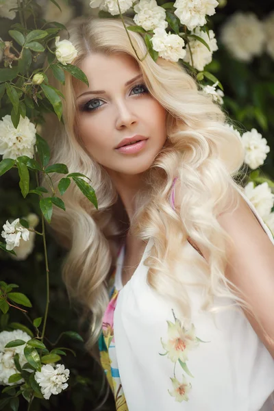 Piękna kobieta w lato Park w pobliżu krzewów kwitnących róż — Zdjęcie stockowe