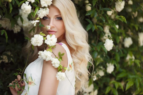 Belle femme dans le parc d'été près du Bush fleurs roses — Photo