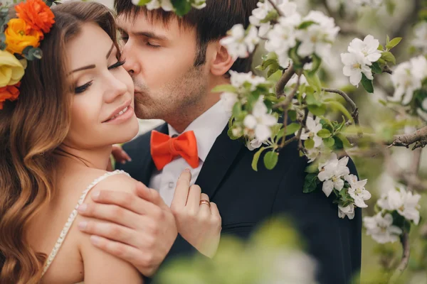 Damat gelini çiçekli parkta baharda kisses.