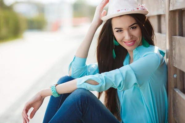 Attractive young woman sitting near the wooden fence — Stock Photo, Image