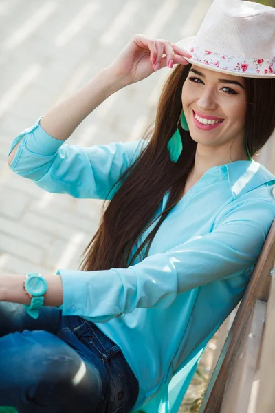 Attractive young woman sitting near the wooden fence — Stock Photo, Image