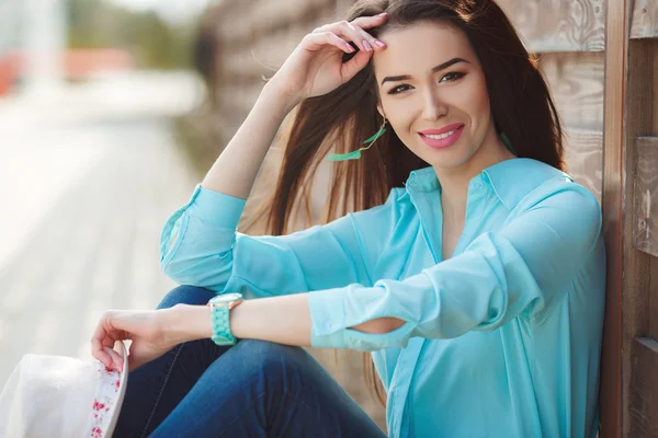 Jolie jeune femme assise près de la clôture en bois — Photo