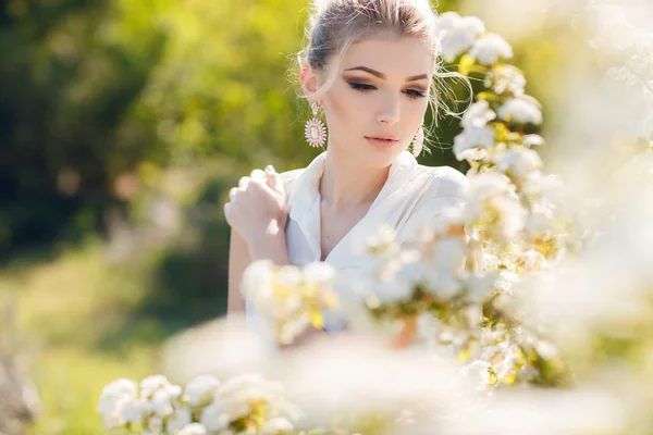 Vacker glad kvinna i en blommig våren trädgård. — Stockfoto