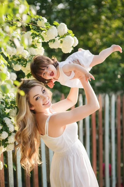 Retrato de mujer feliz con una hija pequeña en el pueblo en la primavera —  Fotos de Stock