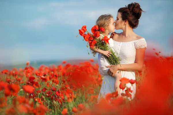 Mother with her little daughter in her arms in a field of blooming poppies. — Stockfoto