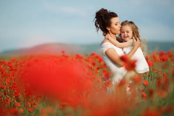 Mutter mit ihrer kleinen Tochter auf dem Arm in einem blühenden Mohnfeld. — Stockfoto